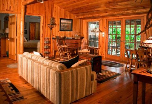 Cozy wooden cabin interior with a striped sofa, rustic furniture, and large windows letting in natural light.