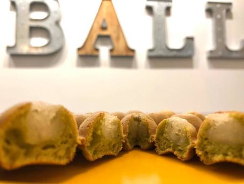 Close-up of green-filled pastries lined up in front of a wall with the word "BALL" in decorative letters.