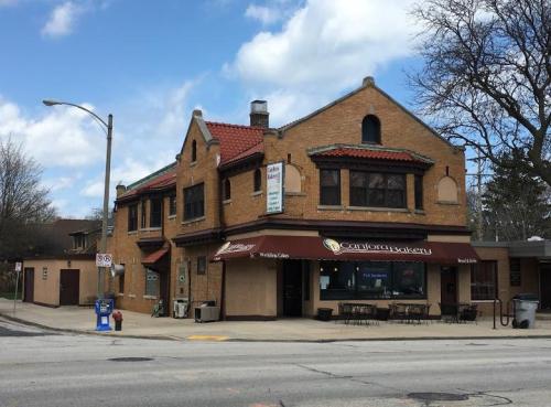 A brick bakery building with a red awning, outdoor seating, and a sign reading "Canton Bakery" under a blue sky.