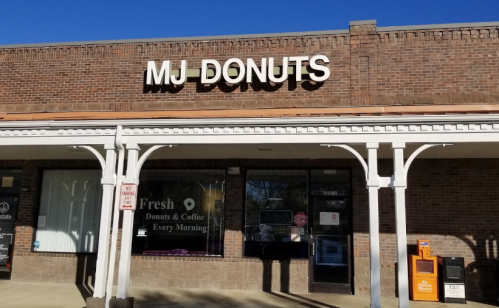 Sign for MJ Donuts on a brick storefront, advertising fresh donuts and coffee every morning.