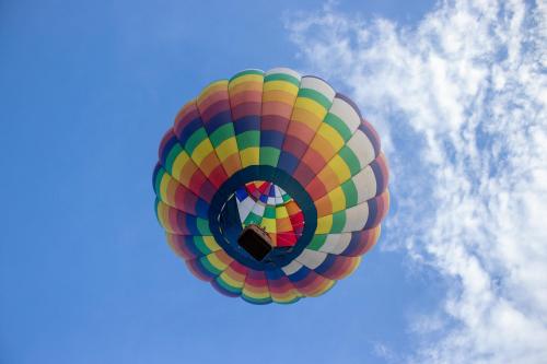A colorful hot air balloon floats against a blue sky with scattered clouds.