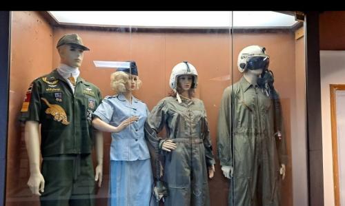 Display of four mannequins in military and aviation uniforms, showcasing historical attire in a glass case.