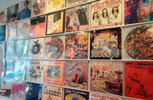 A collage of colorful vintage album covers displayed on a wall, featuring various artists and themes.