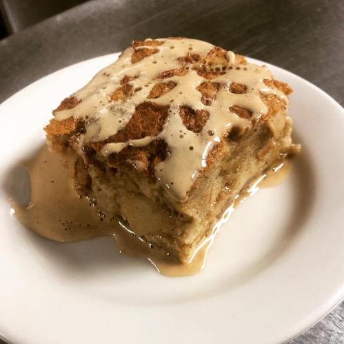A slice of cake drizzled with a creamy sauce, served on a white plate.