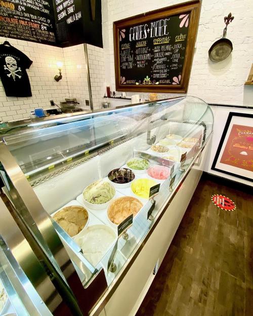 A display case filled with various flavors of ice cream and gelato in a cozy shop setting.