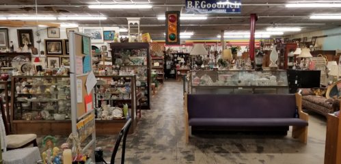 A spacious antique store filled with various collectibles, furniture, and displays under soft lighting.