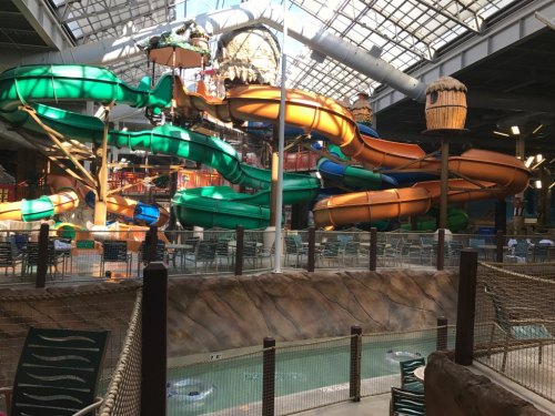 Indoor water park featuring colorful water slides, a lazy river, and a tropical-themed environment.