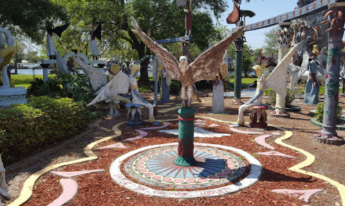 Colorful outdoor art installation featuring various sculptures of birds and figures in a garden setting.