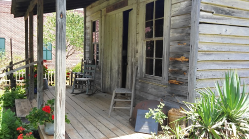 A weathered wooden porch with rocking chairs and potted plants, showcasing rustic charm and a welcoming atmosphere.