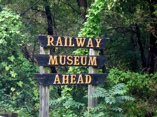 Signpost indicating "Railway Museum Ahead" surrounded by greenery.