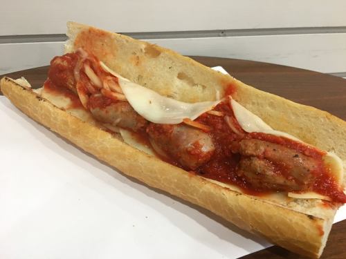 A sub sandwich filled with sausage, marinara sauce, and melted cheese on a crusty bread roll.