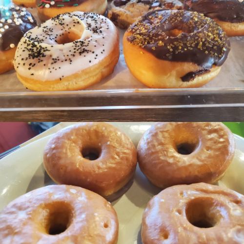 A tray of assorted donuts, including glazed, chocolate, and sprinkled varieties, alongside plain donuts on a plate.