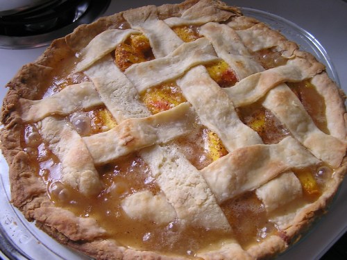 A freshly baked pie with a golden lattice crust, filled with bubbling fruit filling.
