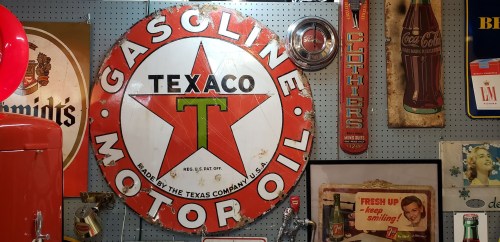 Vintage Texaco gasoline sign with a red star, surrounded by various retro advertisements and memorabilia.