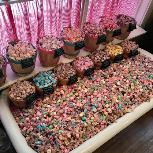 A display of colorful candy in baskets and a tub, featuring various pastel shades and shapes.