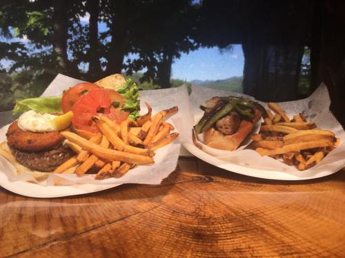 Two plates of burgers with fries: one topped with lettuce, tomato, and a fried patty; the other with grilled vegetables.
