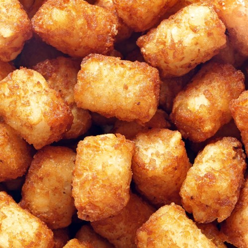 A close-up of golden, crispy tater tots piled together.