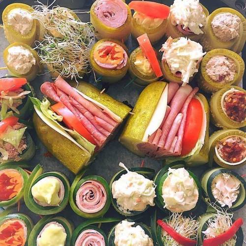 A colorful platter of rolled pickles and cucumbers filled with various meats, cheeses, and toppings.