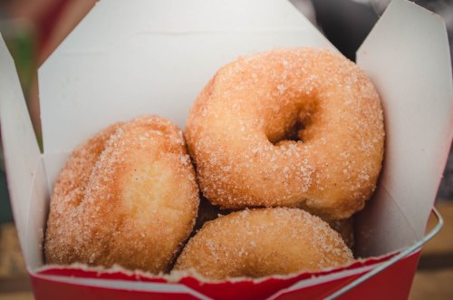 A box filled with freshly made, sugar-coated donuts.