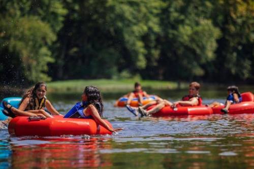 A group of people floating on colorful inner tubes in a calm river, enjoying a sunny day outdoors.