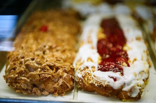 Two pastries side by side: one topped with nuts and caramel, the other with icing and strawberry filling.