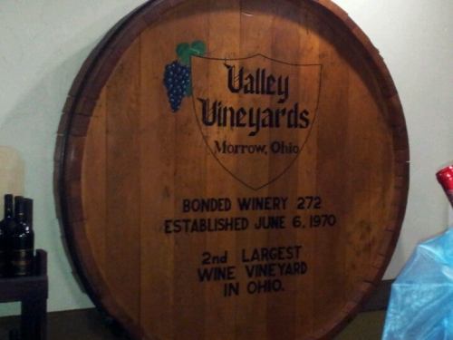 A large wooden wine barrel with "Valley Vineyards, Morrow, Ohio" and details about its establishment and size.