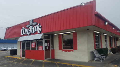 Exterior of Couz'Von's restaurant featuring a red roof and signage, with a parking lot and cloudy sky in the background.