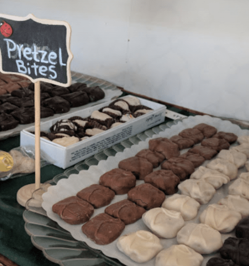 A display of pretzel bites in various chocolate coatings, with a small sign labeling them.
