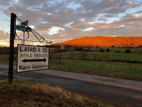 Sign for Laird & Co. Apple Products with a scenic view of a sunset-lit mountain in North Garden, VA.