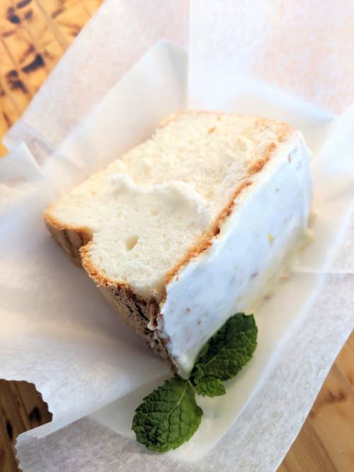 A slice of white bread topped with a creamy spread, garnished with a fresh mint leaf, on a parchment-lined surface.
