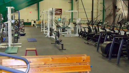 A spacious gym with various exercise equipment, including weight machines, treadmills, and rowing machines.