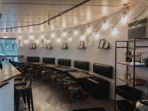 Cozy café interior with string lights, wooden tables, and black seating along the walls.