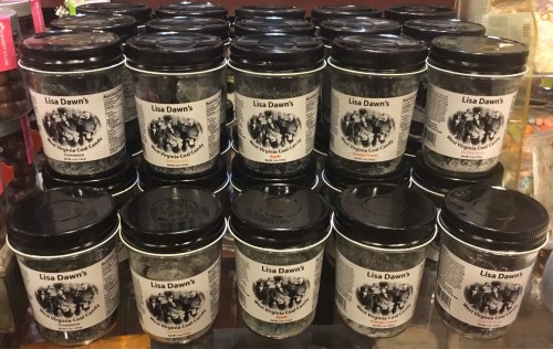 A display of jars labeled "Lisa Dawn's" filled with a gray substance, arranged neatly on a shelf.