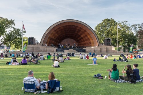 A crowd enjoys a live music performance at an outdoor amphitheater on a sunny day.
