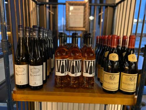 A display of various wine bottles, including red and rosé, arranged on a wooden shelf.