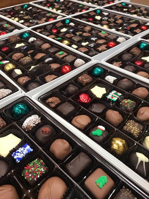 A close-up of assorted chocolates arranged in multiple boxes, featuring various shapes and colorful decorations.