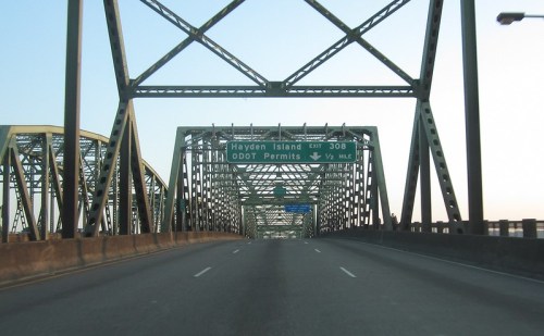 A view of a metal bridge with a highway sign indicating exit for Hayden Island and ODOT permits ahead.