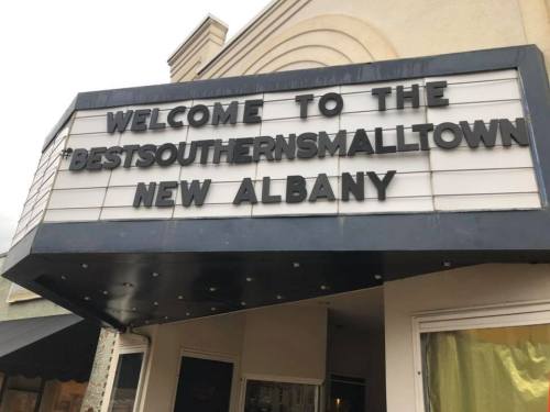 Signboard reading "Welcome to the Best Southern Small Town, New Albany" with a decorative marquee.