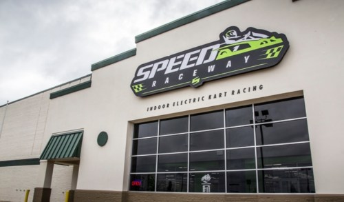 Exterior of Speed Raceway, featuring a large sign and windows, promoting indoor electric kart racing.