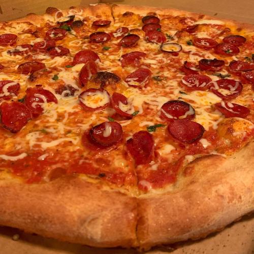 A close-up of a pepperoni pizza with melted cheese and a golden crust on a cardboard base.