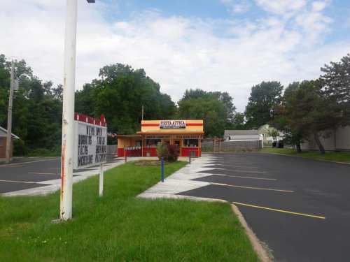 A colorful restaurant building with a large sign, surrounded by green grass and a mostly empty parking lot.