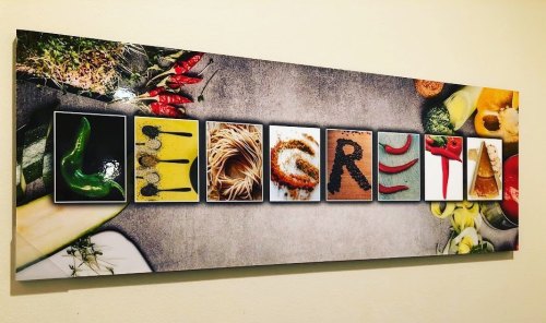 A colorful wall art piece featuring the word "LEMON" spelled out with various food items and spices.