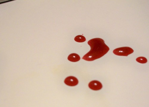 Red paint droplets scattered on a white surface.