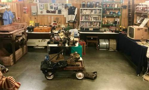 A cluttered vintage shop interior filled with old items, including furniture, books, and various collectibles.