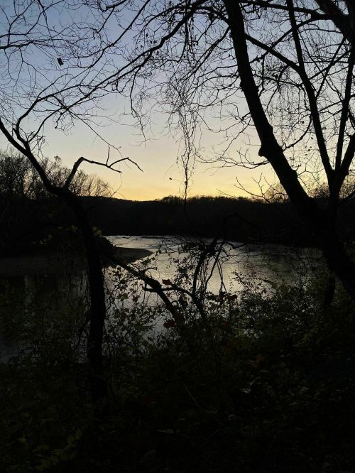 Silhouette of trees framing a calm river at dusk, with a soft gradient sky transitioning to night.