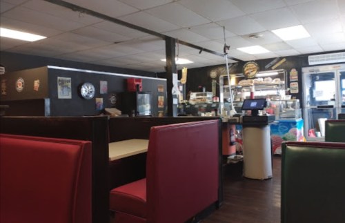 Interior of a diner featuring red and green booths, a counter with a cash register, and vintage decor on the walls.