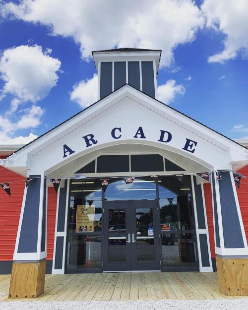 Entrance of an arcade building with a blue sky and clouds above, featuring a large sign that reads "ARCADE."