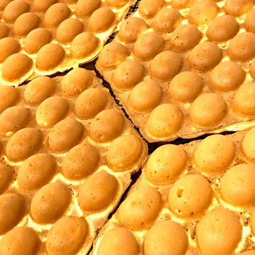 Close-up of golden, egg-shaped pastries arranged on a tray, showcasing their textured surface and round shapes.