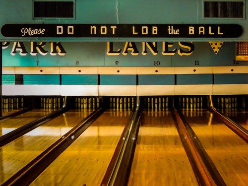 A bowling alley with wooden lanes and a sign that reads "Please DO NOT LOB the BALL" above the lanes.