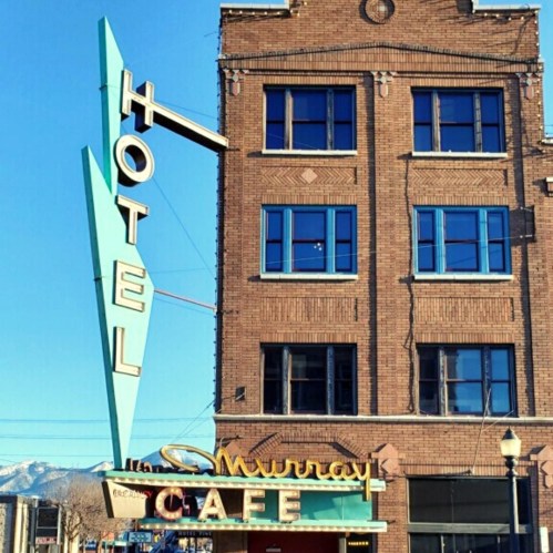 Vintage hotel sign with "Murray Café" below, featuring a retro design and brick building in the background.